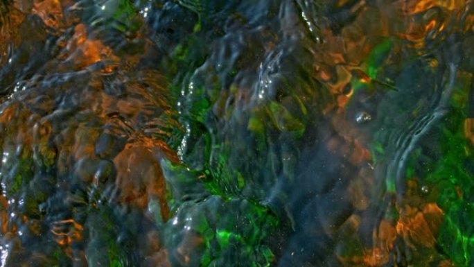 超级SLO MO水沿着一条河流下，地面上有许多绿色和棕色的大块石头