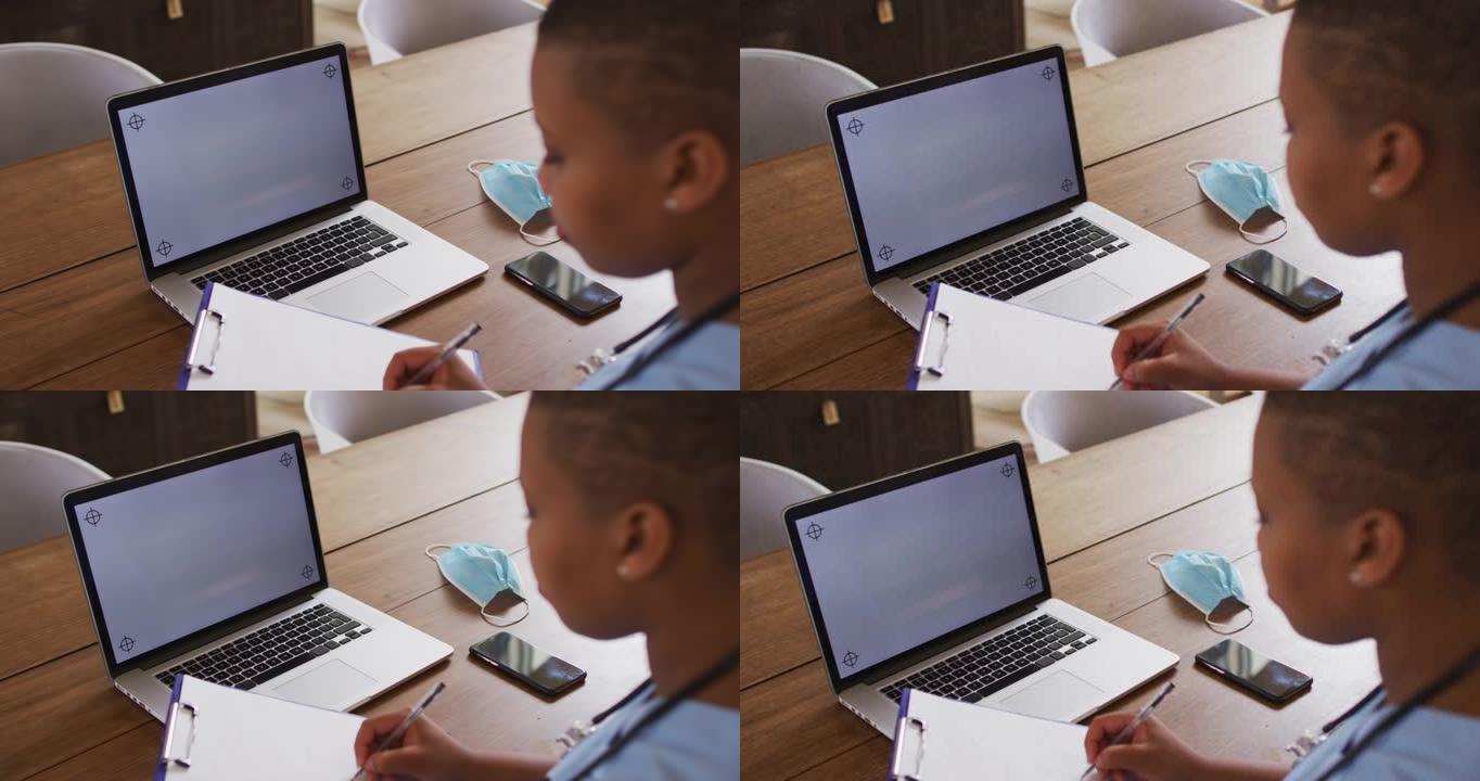 非裔美国女医生在使用带复印空间的笔记本电脑进行视频通话时做笔记