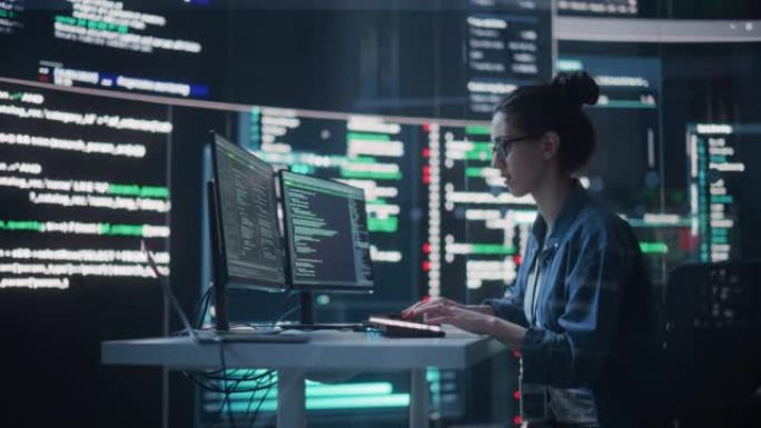 在计算机上工作的女人的肖像，在监控室中键入出现在大屏幕上的代码行。女性程序员使用AI数据和系统创建创