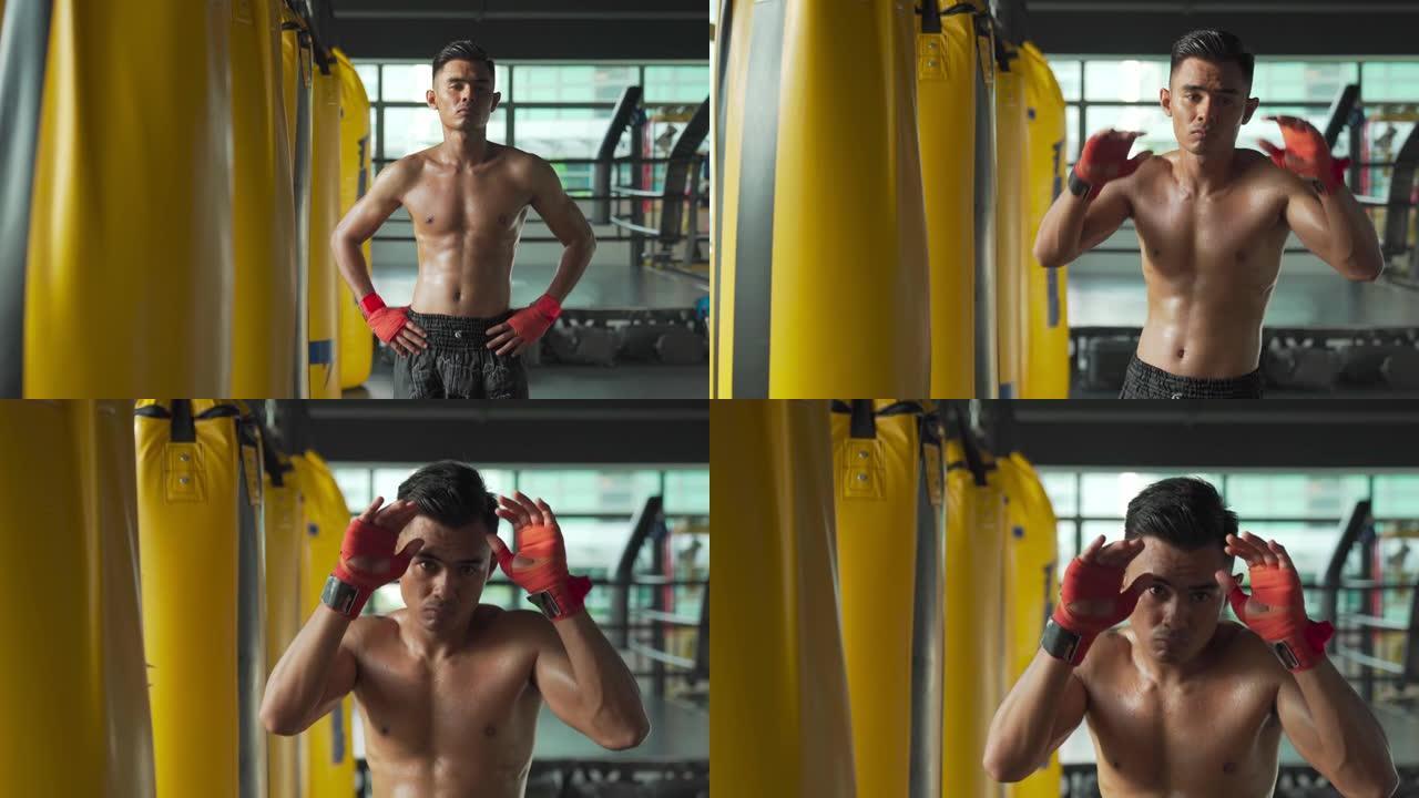 锻炼后，亚洲马来泰拳男运动员肖像在健身房里一排出气筒旁边看着相机