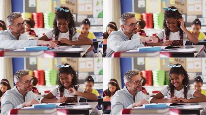 多元化的快乐男老师在学习过程中帮助坐在教室里的女学生