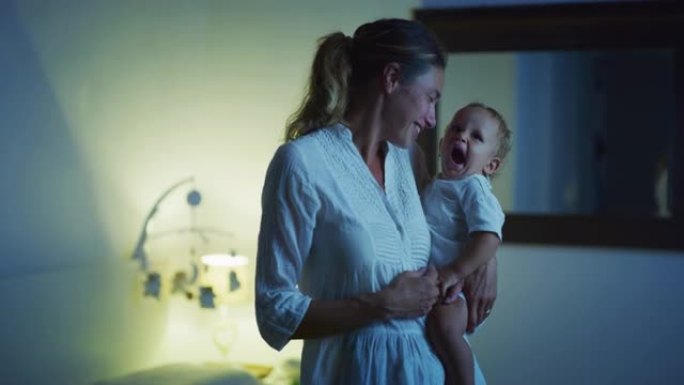 年轻的和平的新母亲的真实电影拍摄是在晚上在托儿所睡觉之前将新生婴儿抱在怀里。