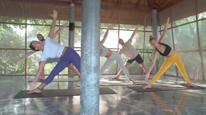 一群年轻的多民族体育课在日出的早晨一起练习瑜伽课，同时被大自然包围。健身课程概念。