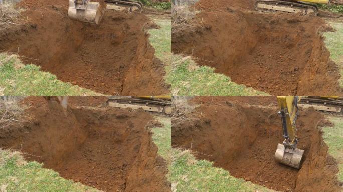 特写: 黄色挖掘机在草地中间挖出一个深洞。
