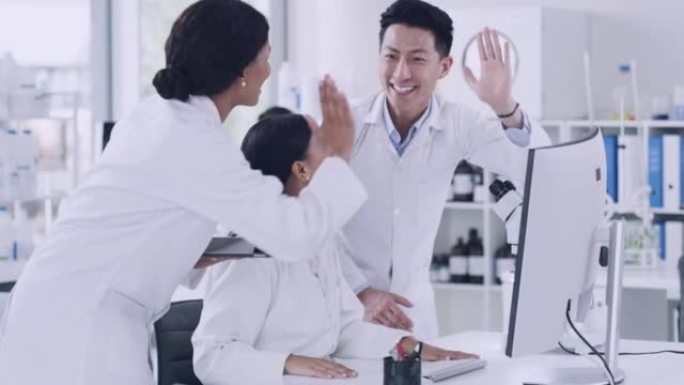 科学家团队在猴痘治疗的基因突破后以高五姿态庆祝。在实验室中使用计算机和显微镜的病理学家和生化工程师的