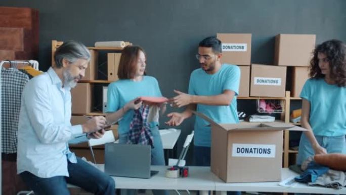 一群志愿者用纸箱包装衣服，而慈善公司经理在办公室的剪贴板上写字