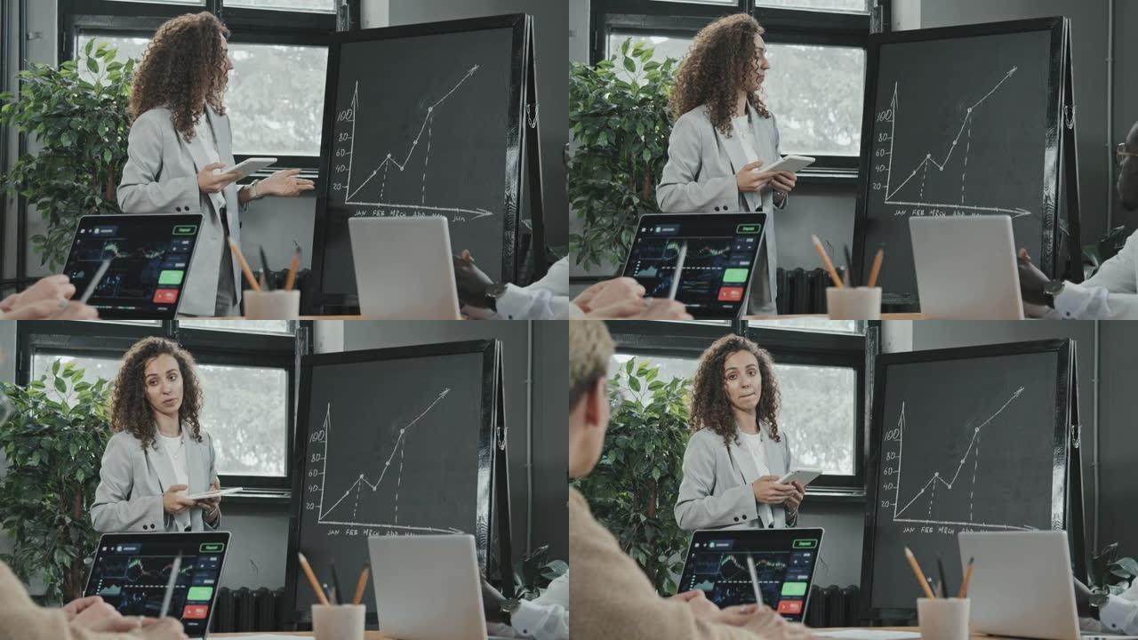 严肃的女商人站在平板电脑上的黑板上