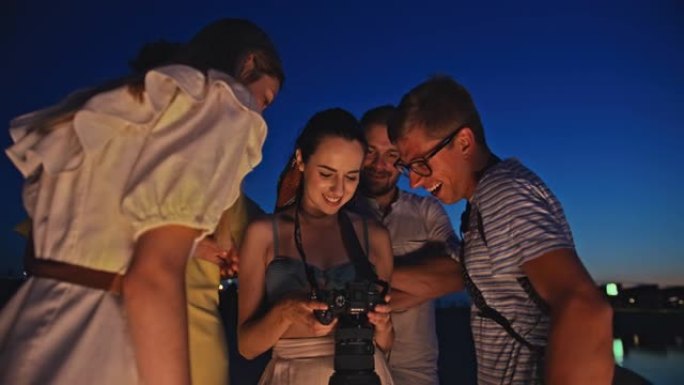 SLO MO年轻女子在蓝色时刻向她的朋友展示相机上的照片