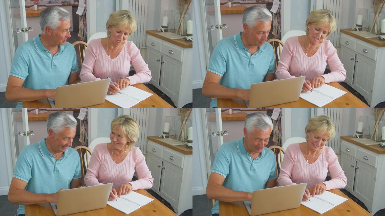 老年退休夫妇坐在家里的桌子上，用笔记本电脑评估个人财务状况