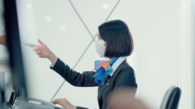 亚洲航空公司女职员在登机台戴上口罩，将护照交给乘客。