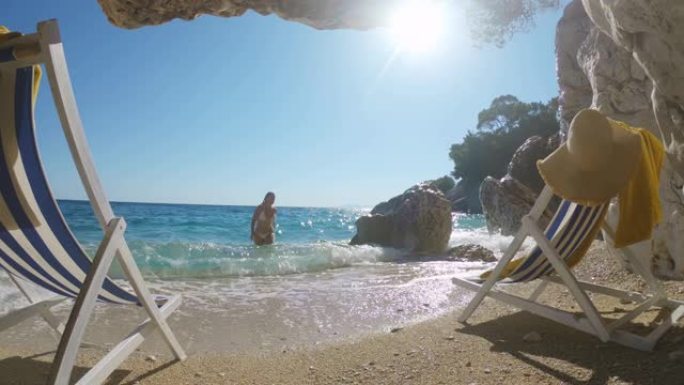 女士年轻女子在克罗地亚亚得里亚海海滩洞穴外的阳光明媚的海洋冲浪中涉水