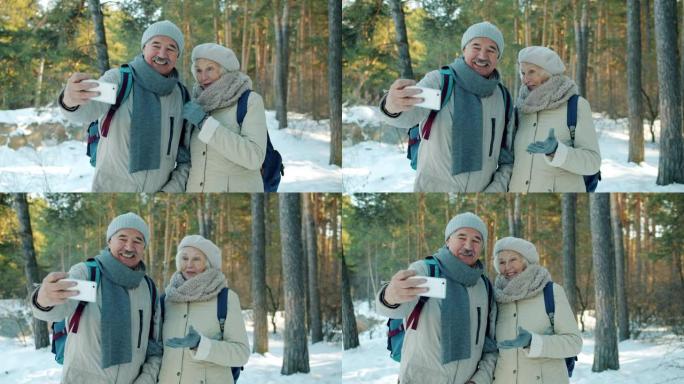 使用智能手机摄像头在冬季公园自拍的高级男女慢动作