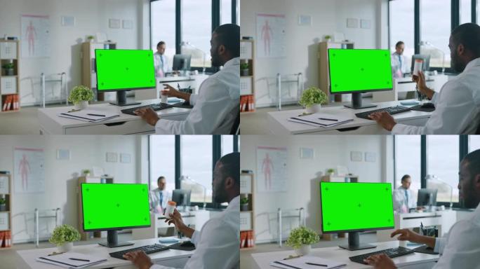 非裔美国医生正在健康诊所的绿屏显示的计算机上与患者进行视频通话。穿着实验室外套的助理正在医院办公室谈