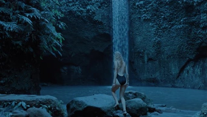 性感的女人看着雨林丛林中的瀑布独自探索，穿着泳衣4k享受异国旅行假期