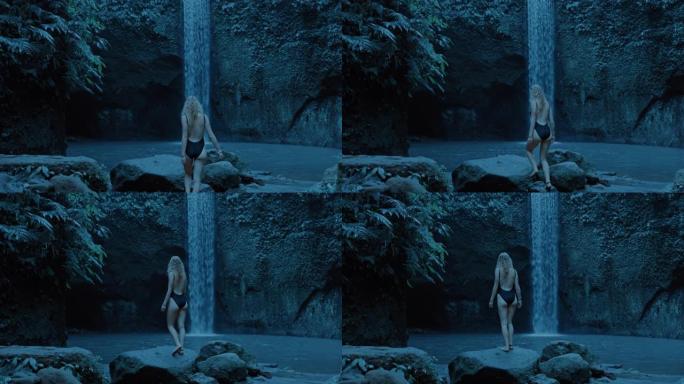 性感的女人看着雨林丛林中的瀑布独自探索，穿着泳衣4k享受异国旅行假期