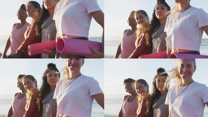 一群不同的女性朋友在海滩上拿着瑜伽垫