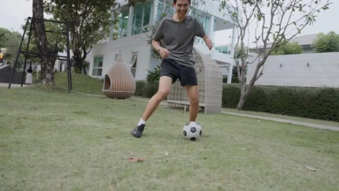亚洲快乐的手臂残疾年轻人在球场上踢足球。