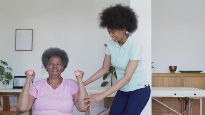 快乐的非洲裔美国女理疗师帮助高级女病人在家锻炼
