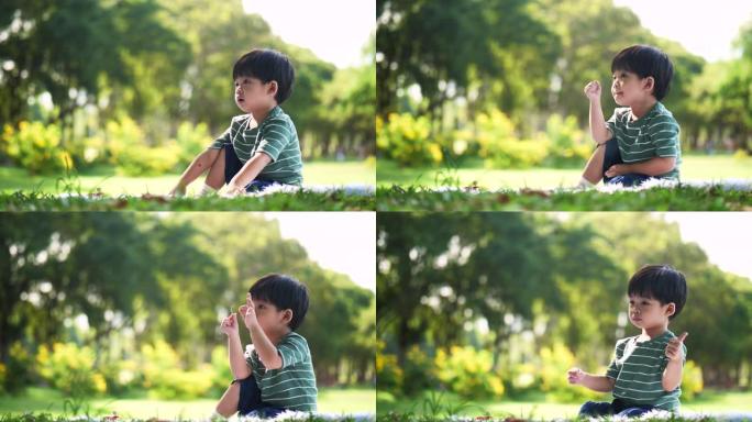 小男孩坐在花园里玩彩虹风车
