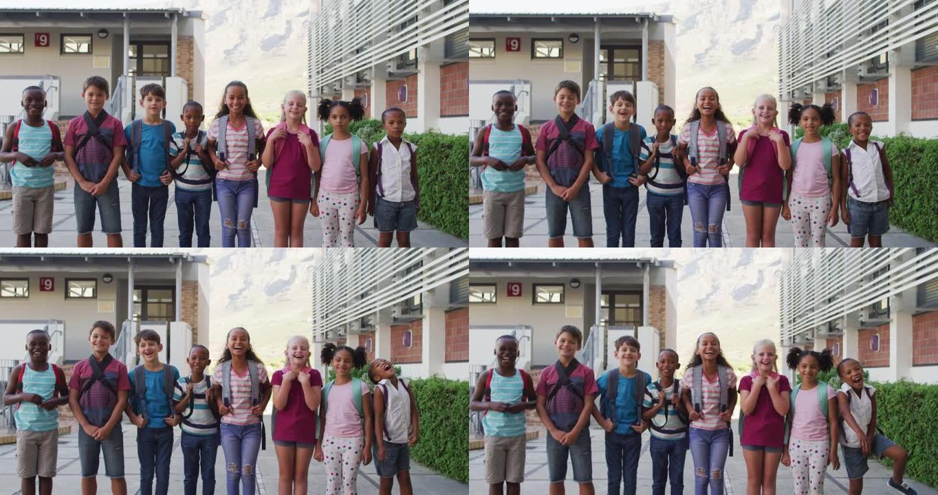 各种各样的学童穿着背包微笑着站在学校院子里排成一排
