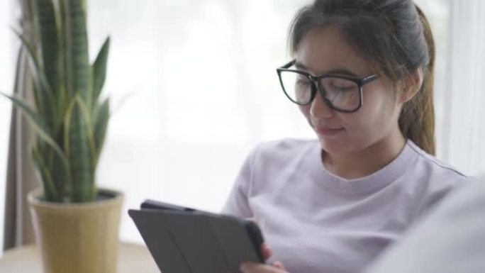 年轻女子在家在客厅放松，使用数字平板电脑