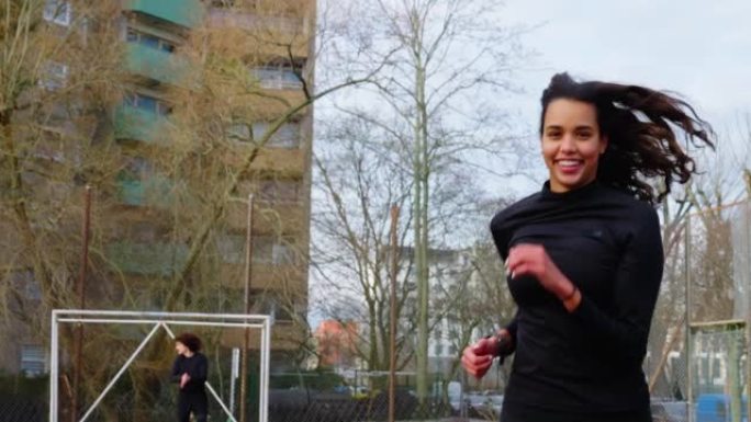 年轻的西班牙裔妇女在城市足球场上奔跑