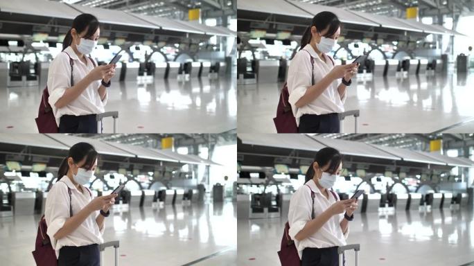 亚洲妇女在机场使用智能手机戴口罩