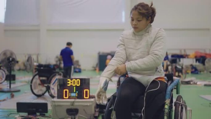 女轮椅击剑运动员整理制服。