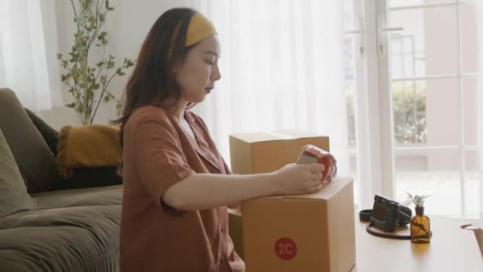 亚洲女老板包装纸箱得到邮政包裹。