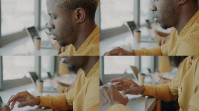 年轻成功的美国黑人商人在共享办公室使用笔记本电脑的俯仰肖像