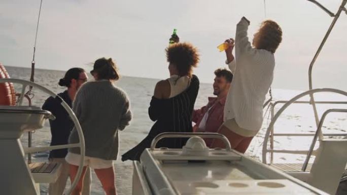 SLO MO年轻人在日落时在船的甲板上举行聚会
