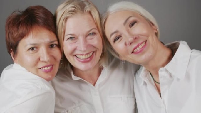 三个成熟女友在镜头前微笑的工作室肖像
