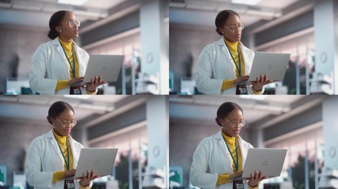 穿着实验室外套的年轻黑人女性专家的肖像微笑着使用笔记本电脑。专业而成功的女性担任工程师，思考和开发高