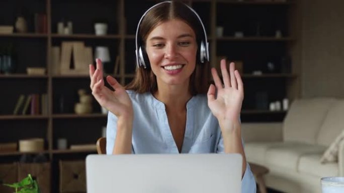 女人戴着耳机通过笔记本电脑上的视频与朋友交谈