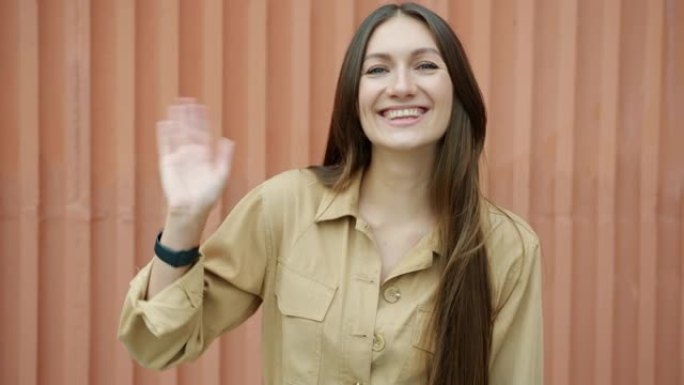 站在外面的迷人女孩挥手微笑的慢动作肖像