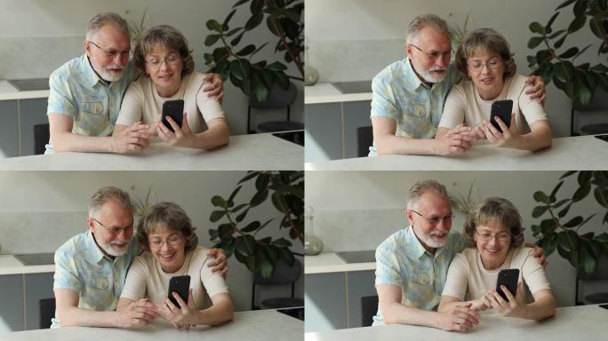 友好的高级祖父母拥抱在厨房观看电话视频