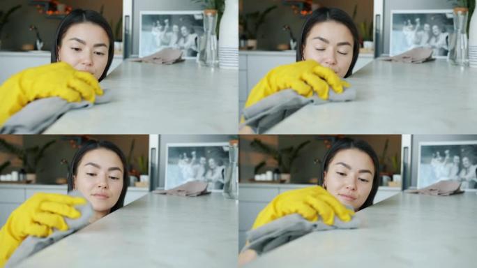 美丽的亚洲家庭主妇在现代公寓用湿布独自做家务打扫厨房的肖像