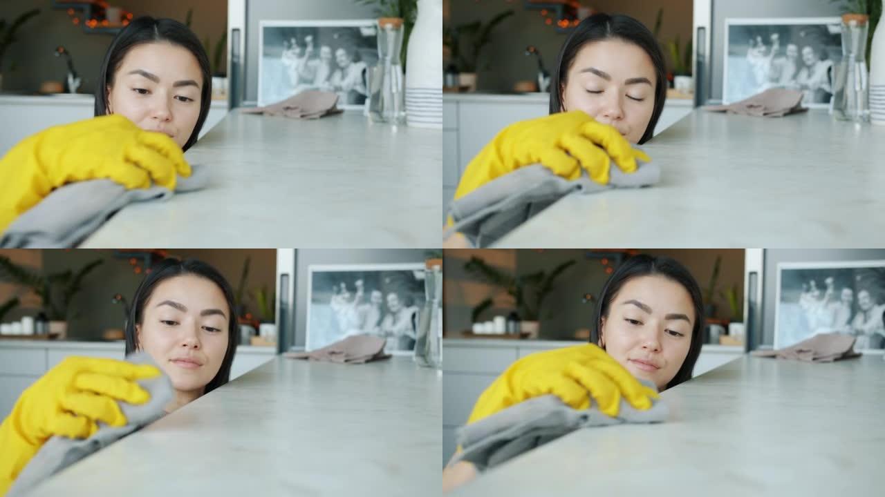 美丽的亚洲家庭主妇在现代公寓用湿布独自做家务打扫厨房的肖像