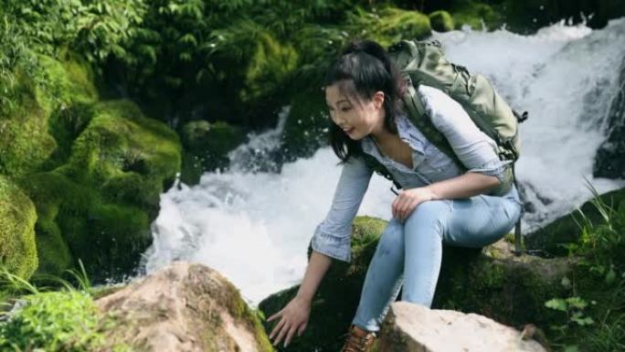 坐在瀑布边的女徒步旅行者休息一下