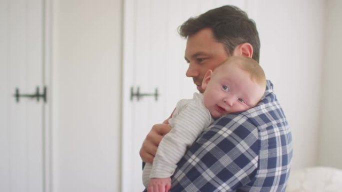 慈爱的父亲拥抱婴儿儿子一起在家里休息