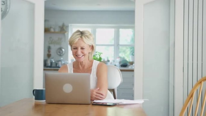 退休的高级妇女在家中使用笔记本电脑与家人进行视频通话