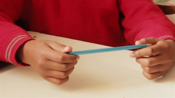 坐在课桌上的男生在课堂上从老师那里收到一把塑料尺和白纸。特写。