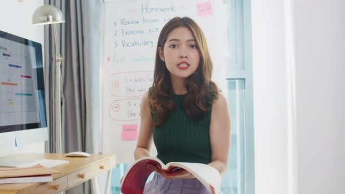 亚洲年轻女英语教师视频会议看着摄像头说话，通过摄像头学习教学，在网上聊天在家。