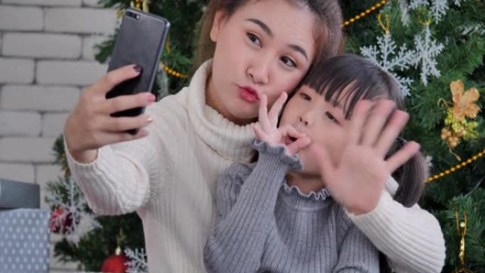 6岁的亚洲母女在使用智能手机和视频会议技术进行社交距离期间在家中客厅视频通话的视频会议。社交电话会议