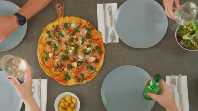 意大利餐厅的朋友在一起吃披萨之前用葡萄酒和啤酒烤面包的俯视图-慢动作拍摄