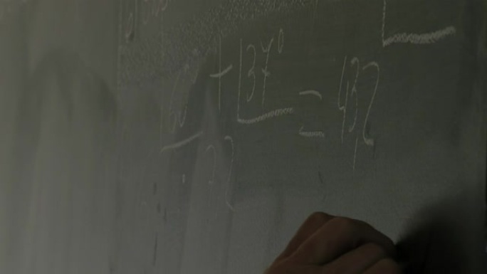在阿根廷监狱为囚犯举行的教育课上，一名男老师在绿色黑板上写字。特写。