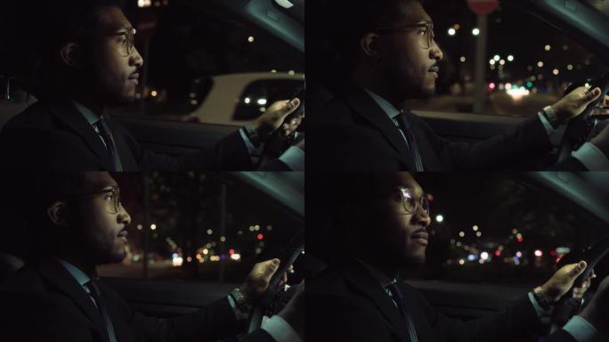 一个穿着西装的英俊黑人的肖像在晚上驾驶一辆豪华汽车，专注于道路。成功的非洲裔美国商人安全开车下班，思