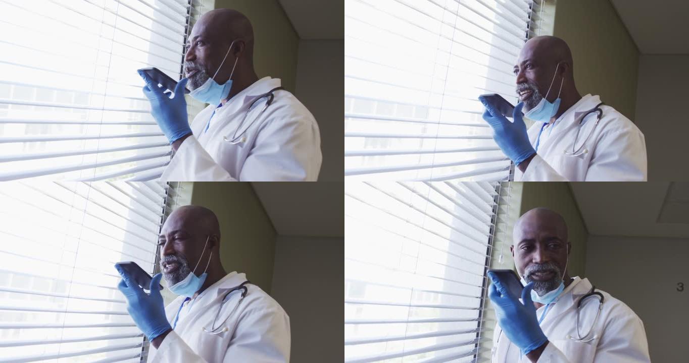 戴着口罩的非洲裔美国男性医生使用智能手机交谈的肖像