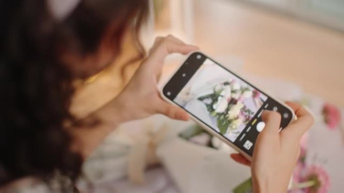年轻的亚洲女性在商店里用智能手机摆放新鲜切花和拍照。