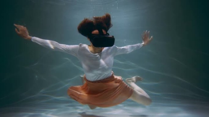 虚拟现实。快乐混血女人在增强耳机界面眼镜漂浮在水下慢动作。